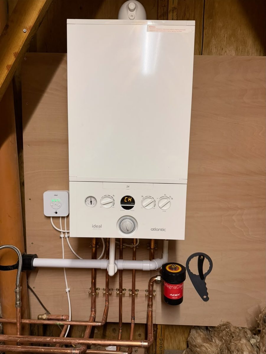 Ideal Atlantic boiler mounted on a boarded loft wall beneath the rafters, with a copper manifold and a MagnaClean filter below